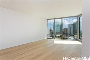 unfurnished room featuring hardwood / wood-style floors and a wall of windows