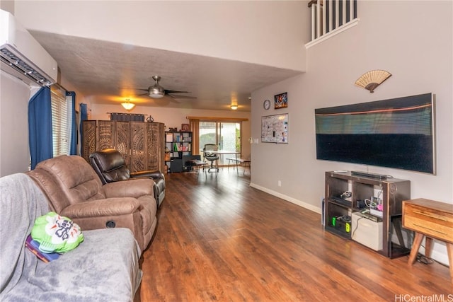 living room with hardwood / wood-style floors, a wall unit AC, and ceiling fan