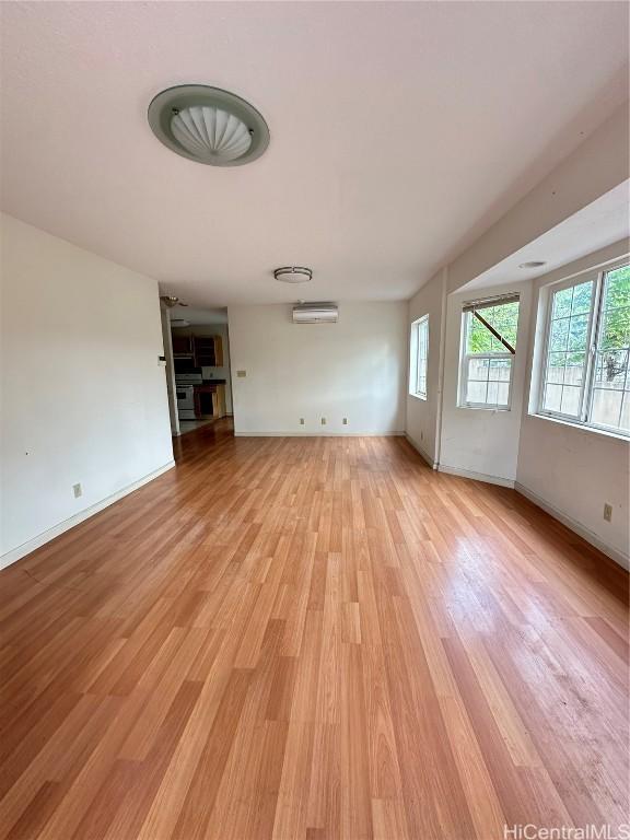 unfurnished living room featuring a wall mounted AC and light hardwood / wood-style flooring