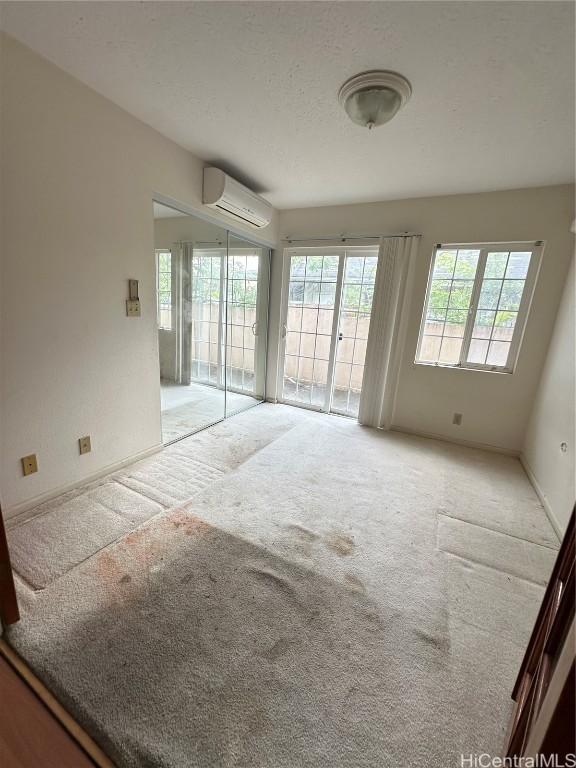 unfurnished room featuring light colored carpet and a wall mounted air conditioner