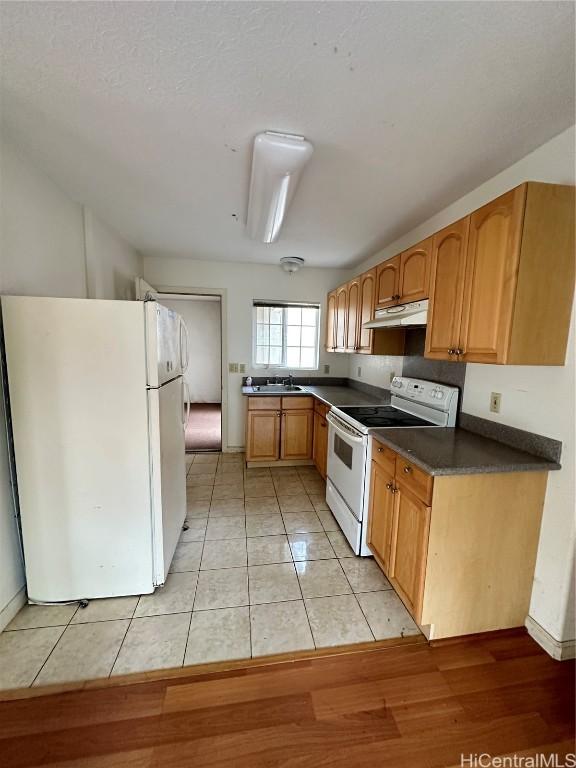 kitchen with light tile patterned floors, white appliances, and sink