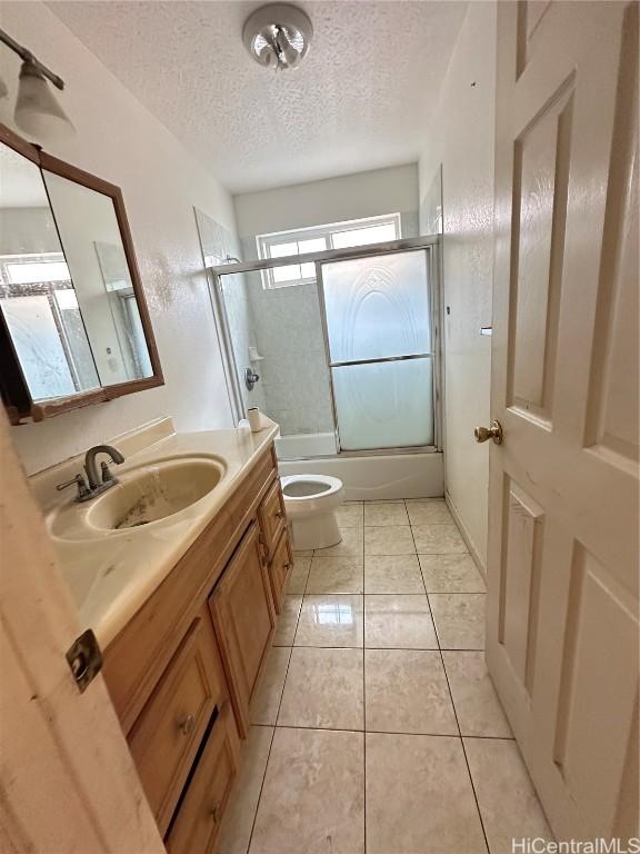 full bathroom with vanity, shower / bath combination with glass door, tile patterned floors, toilet, and a textured ceiling