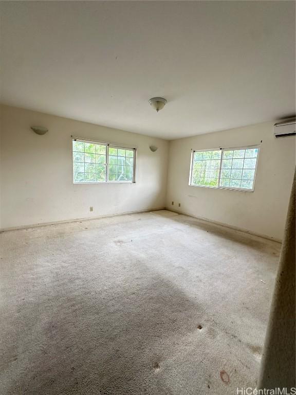 empty room featuring carpet and a wall mounted air conditioner