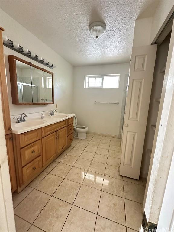 bathroom with tile patterned flooring, vanity, and a textured ceiling