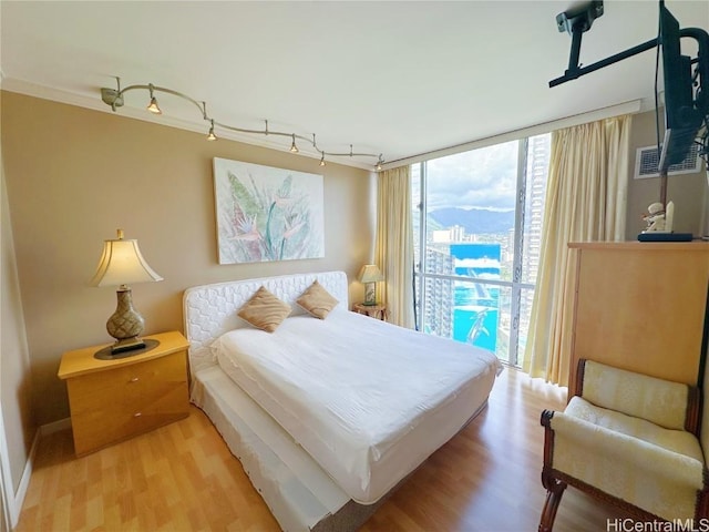 bedroom featuring a wall of windows and light hardwood / wood-style floors