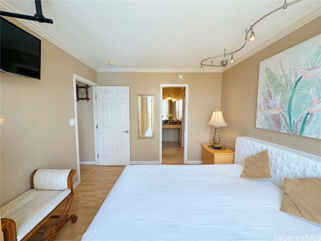 bedroom featuring light wood-type flooring, crown molding, and connected bathroom