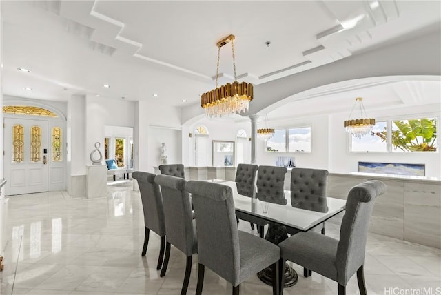 dining space featuring decorative columns, a notable chandelier, and a healthy amount of sunlight