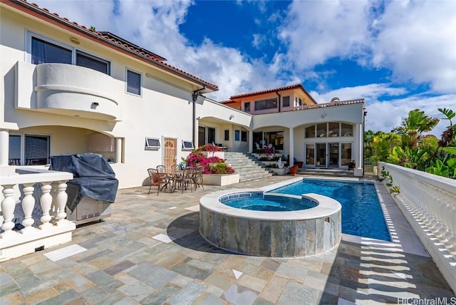 rear view of house with a swimming pool with hot tub and a patio area