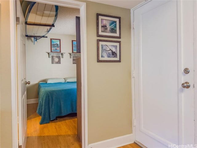 hall featuring light hardwood / wood-style floors and a textured ceiling