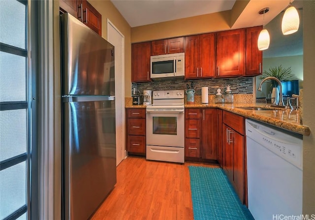 kitchen featuring pendant lighting, white appliances, backsplash, sink, and light wood-type flooring