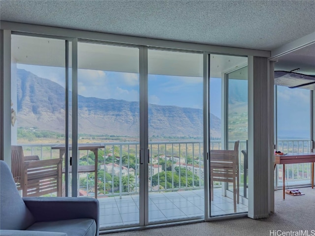 doorway to outside featuring carpet flooring, a mountain view, and a textured ceiling