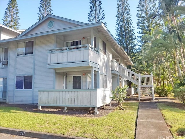 view of home's exterior featuring a balcony and a yard