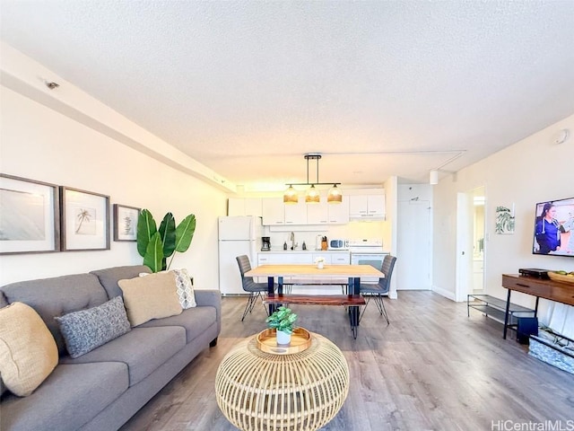 living room featuring sink, light hardwood / wood-style floors, and a textured ceiling