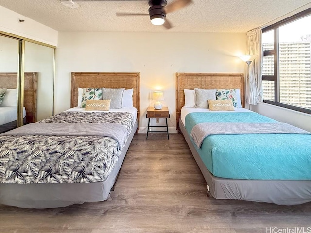 bedroom featuring ceiling fan, wood-type flooring, a textured ceiling, and a closet