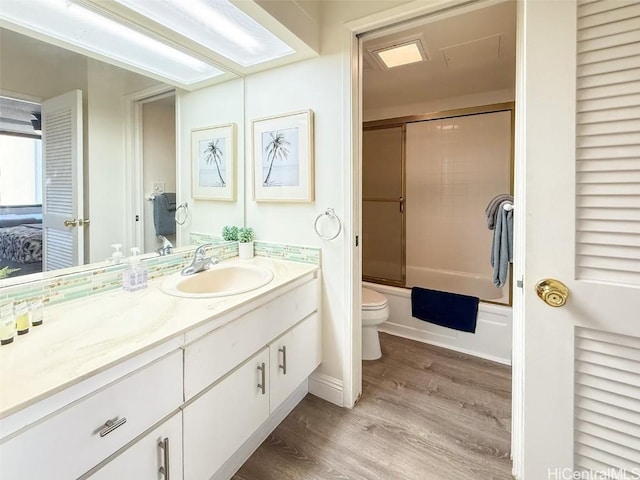 full bathroom with toilet, vanity, bath / shower combo with glass door, and hardwood / wood-style flooring