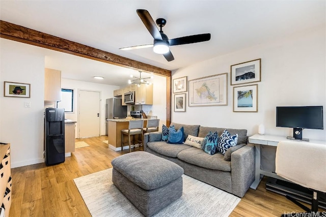 living room featuring ceiling fan with notable chandelier, beam ceiling, and light hardwood / wood-style floors