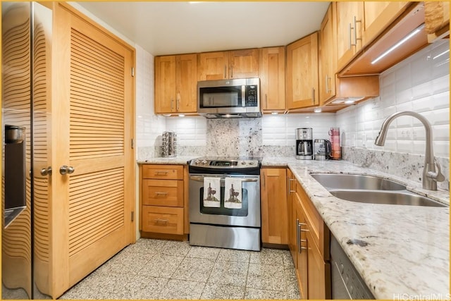 kitchen featuring appliances with stainless steel finishes, tasteful backsplash, light stone counters, and sink