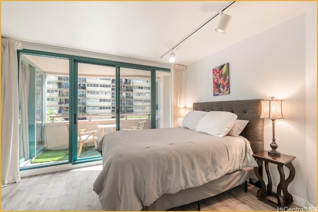 bedroom featuring access to exterior, hardwood / wood-style floors, and rail lighting