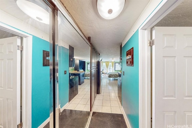 hall featuring light tile patterned flooring and a textured ceiling