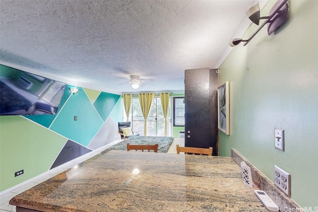 interior space with ceiling fan, a textured ceiling, and light tile patterned floors