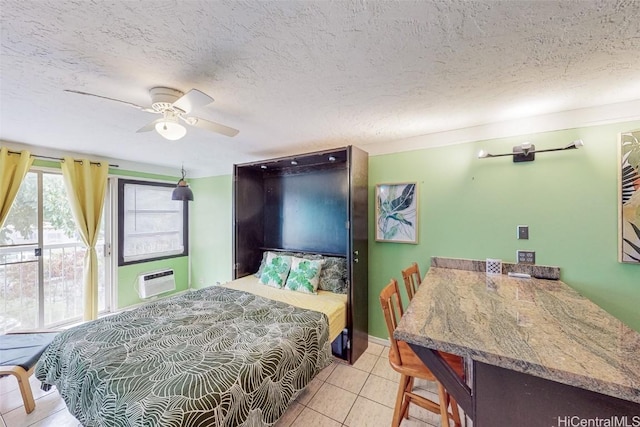 bedroom with an AC wall unit, light tile patterned floors, a textured ceiling, and ceiling fan