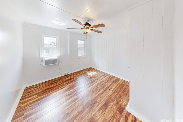 empty room featuring hardwood / wood-style floors, a ceiling fan, ornamental molding, cooling unit, and baseboards