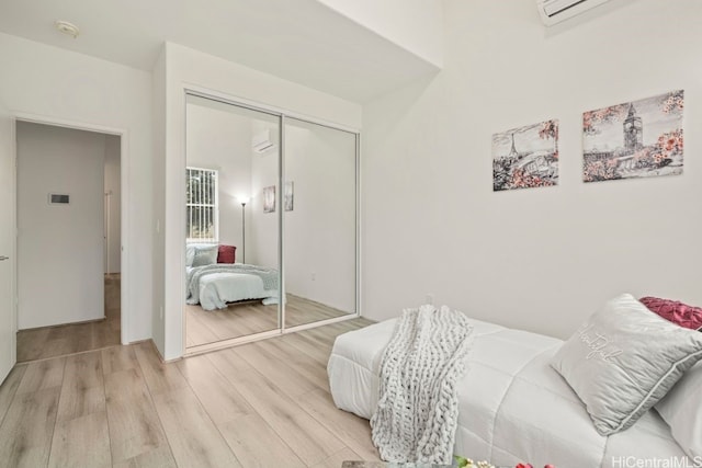 bedroom featuring light hardwood / wood-style flooring, a closet, and a wall unit AC