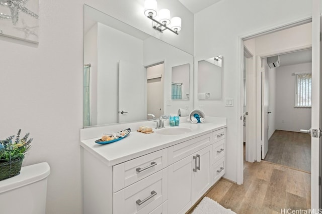 bathroom with a wall mounted air conditioner, vanity, hardwood / wood-style flooring, and toilet