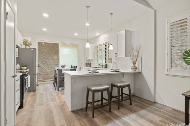 kitchen with stainless steel range with electric cooktop, sink, white cabinetry, and kitchen peninsula