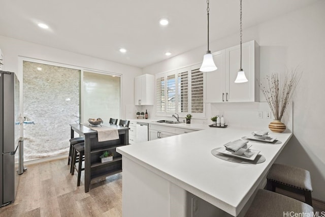 kitchen with white cabinetry, sink, kitchen peninsula, pendant lighting, and appliances with stainless steel finishes