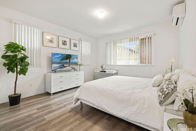 bedroom with light wood-type flooring and a wall unit AC