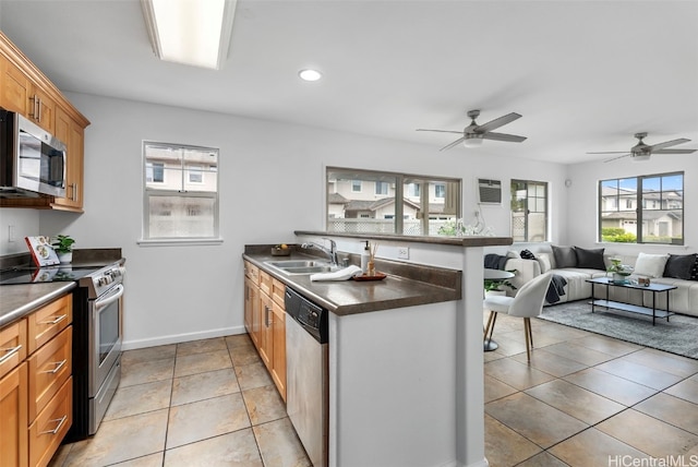 kitchen with ceiling fan, sink, kitchen peninsula, light tile patterned floors, and appliances with stainless steel finishes