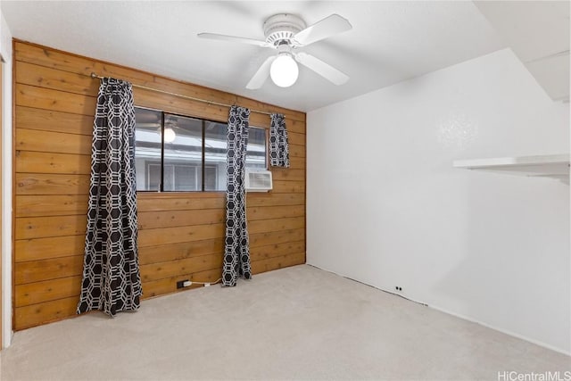 carpeted empty room featuring ceiling fan and wood walls