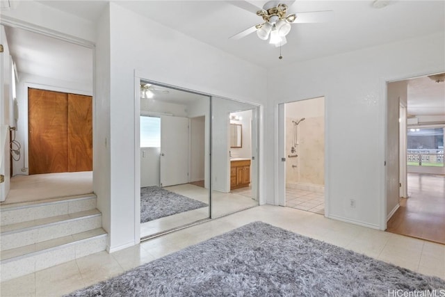 interior space with connected bathroom, ceiling fan, and a closet