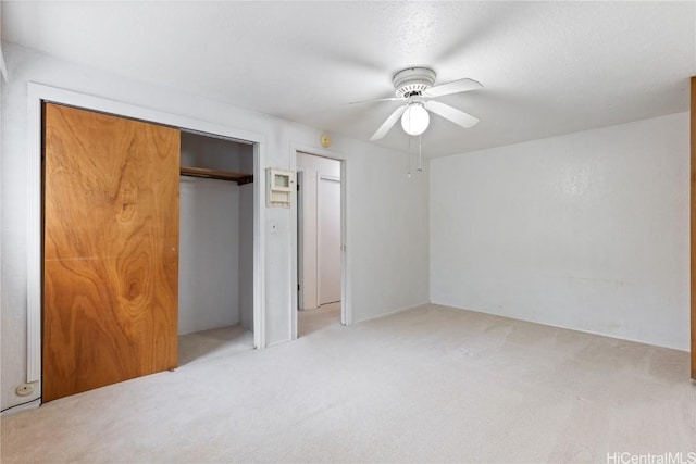 unfurnished bedroom featuring a closet, light colored carpet, and ceiling fan