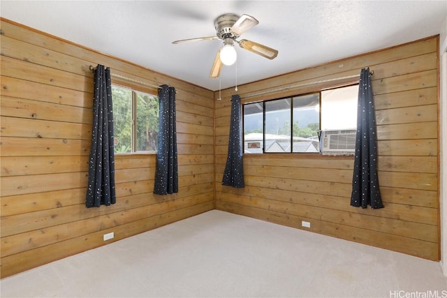 carpeted spare room featuring wooden walls, cooling unit, and ceiling fan