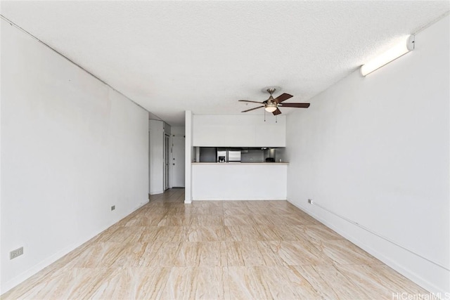 unfurnished living room featuring ceiling fan and a textured ceiling