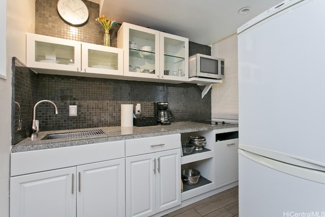 kitchen with decorative backsplash, white fridge, white cabinetry, and sink