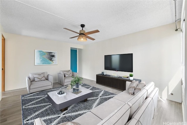 living room with ceiling fan, hardwood / wood-style floors, and a textured ceiling