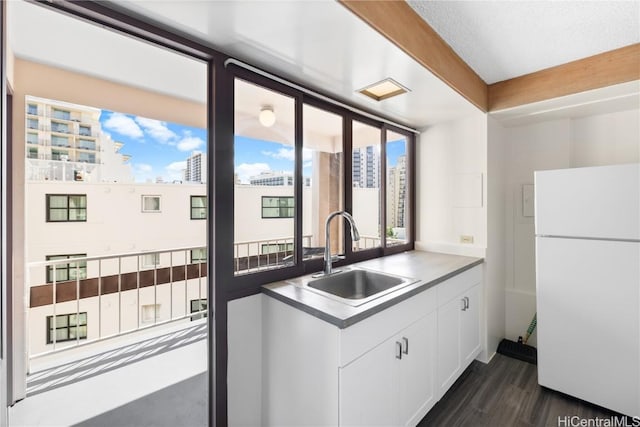 kitchen featuring a wealth of natural light, sink, white cabinets, and white refrigerator