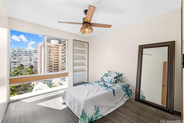 bedroom featuring hardwood / wood-style floors, ceiling fan, a textured ceiling, and multiple windows