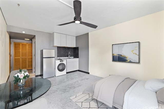 bedroom with washer / dryer, stainless steel refrigerator, ceiling fan, and sink