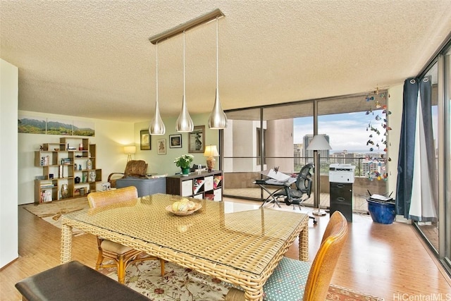 dining area with a textured ceiling, light hardwood / wood-style floors, and floor to ceiling windows