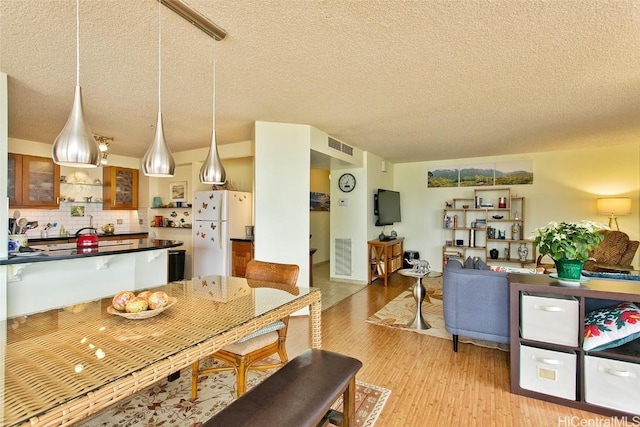 dining area with a textured ceiling and light hardwood / wood-style floors