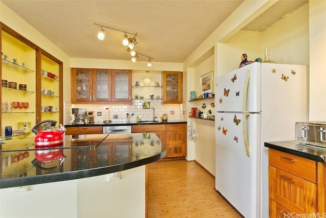 kitchen featuring tasteful backsplash, stainless steel dishwasher, a textured ceiling, white refrigerator, and light hardwood / wood-style flooring