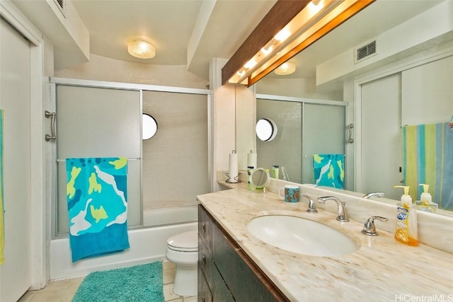 full bathroom with tile patterned floors, vanity, bath / shower combo with glass door, and toilet