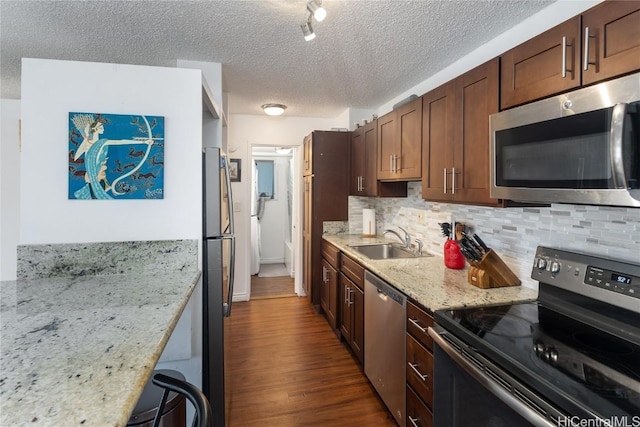 kitchen featuring sink, decorative backsplash, light stone countertops, appliances with stainless steel finishes, and dark hardwood / wood-style flooring