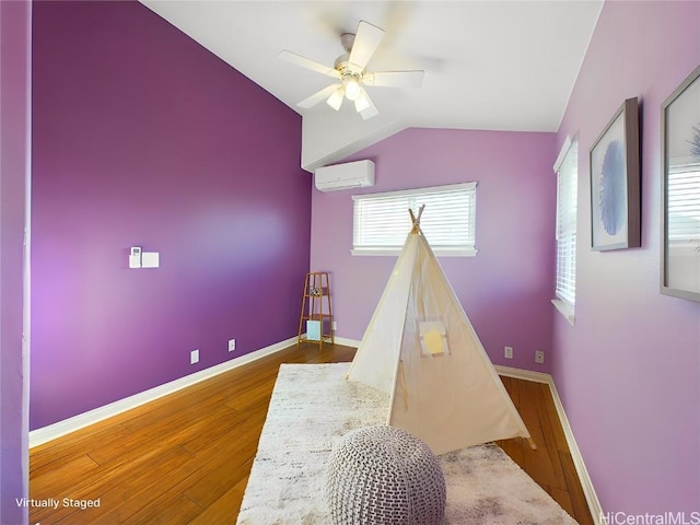 recreation room with hardwood / wood-style flooring, ceiling fan, lofted ceiling, and a wall unit AC