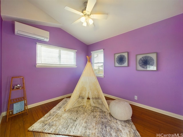 recreation room featuring dark hardwood / wood-style floors, ceiling fan, lofted ceiling, and a wall unit AC