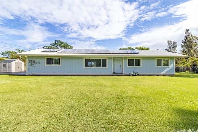 single story home featuring a front yard, a storage unit, and solar panels